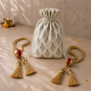 Nar pomegranate tiebacks styled beside a printed drawstring gift pouch with a diya and marigold petals