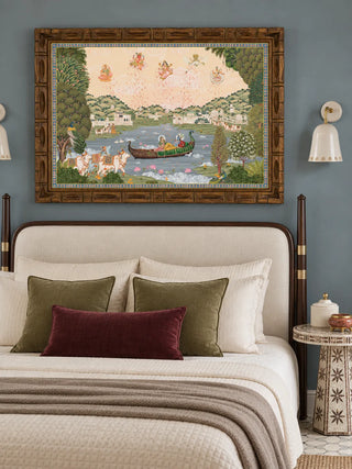 The Nauka-Vihar wall art in a carved wooden frame above an upholstered bed with olive and burgundy cushions on a slate-blue wall.