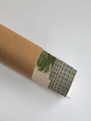 The Nauka-Vihar wall art print partly unrolled from its kraft paper tube, revealing a leafy green panel and the blue floral border.