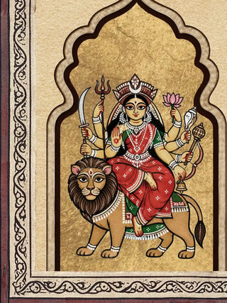 A detailed macro close-up of the Navadurga Virajitam highlighting a seated goddess on a lion within a gold-ground cusped arch and patterned border