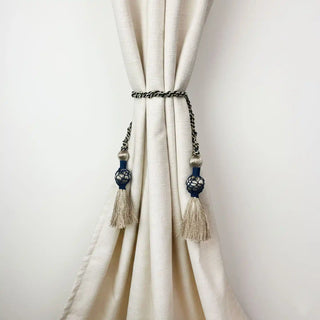 Regal Twist Handcrafted Curtain Holdback secured around a cream curtain, showcasing the dramatic color contrast of the navy and gold.