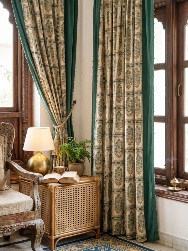 pair of Nayab curtains framing a window in a traditional room with carved wood furniture and a brass lamp.