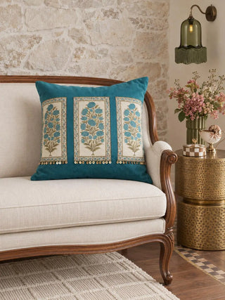 The Nayab velvet cushion cover in Teal on a cream upholstered sofa, styled with brass side tables and fresh flowers.