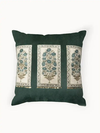 A studio front view of the Nayab dark green velvet cushion showing three embroidered botanical panels and gold coin fringe.