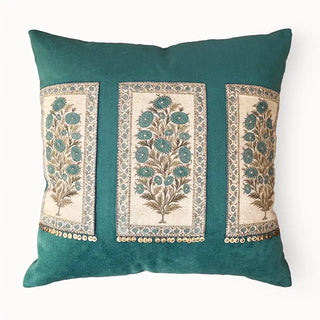 A studio front view of the Nayab teal velvet cushion showing three embroidered panels and gold coin fringe.
