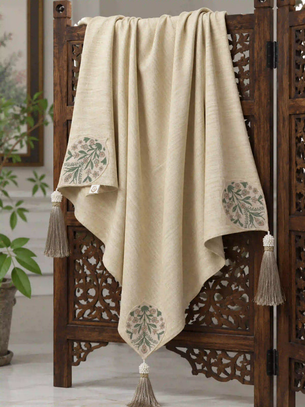 The Nazneen custom hand-embroidered linen throw displayed symmetrically over an openwork dark brown wooden folding privacy screen.