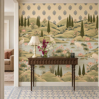 The Neer Kamal wallpaper in an entryway behind a carved dark-wood console with a frilled lamp and a vase of flowers, cranes and lotuses beyond view-foyer