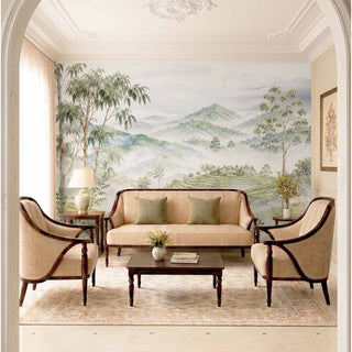 The Nilgiri scenic tea plantation wallpaper mural dressing a living room feature wall behind a beige sofa and wooden coffee table.