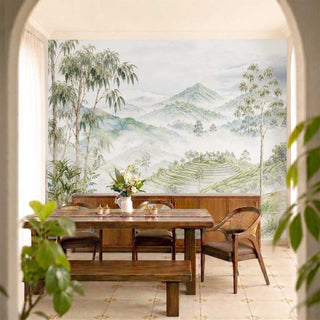 The Nilgiri landscape wallpaper mural installed on a feature wall inside a formal dining room with a solid wooden dining table set.