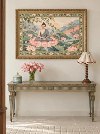 Nirvana Bloom landscape wall art in a carved gold frame above a sage console table holding pink lotus flowers and a scalloped-shade lamp.