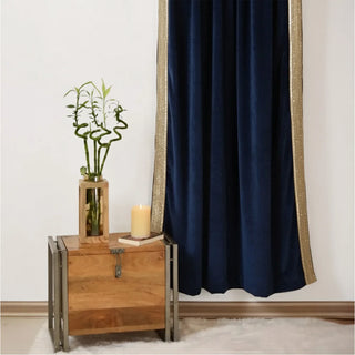 Living room styled with Nizam Blue Gold Curtain, featuring rich navy blue velvet fabric bordered with subtle gold trim, paired with a wooden side chest and decor.