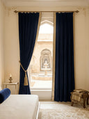 Nizam Navy blue curtains with gold tassels in a room with a view of an outdoor fountain.