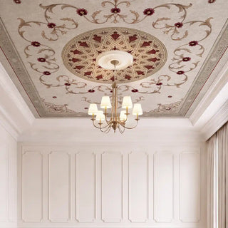A direct look-up view of the Noor Mahal ceiling wallpaper installed on a white molding ceiling around a classic brass chandelier view-ceiling