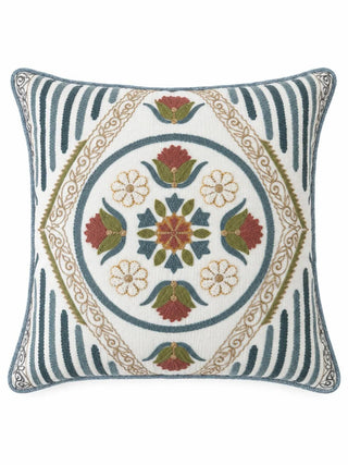 The Noorani embroidered cushion cover showing a blue ring of red blooms and white flowers around a star rosette, inside a gold scrollwork diamond
