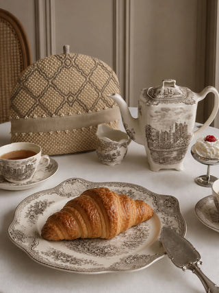 Oat Pearl tea cosy with pearl-beaded trim styled beside a vintage teapot and croissant on a breakfast table