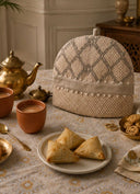 Oat Pearl tea cosy on a printed tablecloth with a brass teapot, clay chai cups and samosas