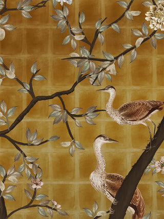 A detailed macro close-up of the Oriental Garden Chinoiserie wall art highlighting two herons among blossoming branches on a mustard-gold trellis ground.