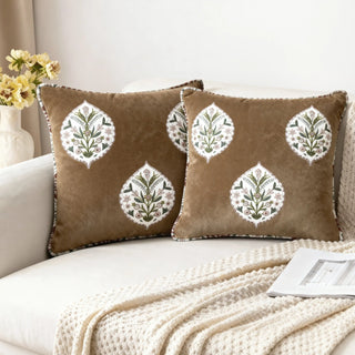 A pair of Gulmohar Noor Buta Cushions placed on a white sofa in a bright setting.