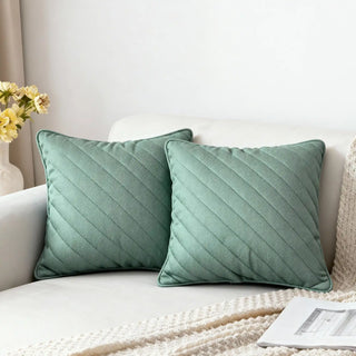 Two Moss Drift Cushions styled on a white sofa with a knitted throw.