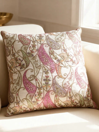 A luxury Paisley Vine cushion featuring multi-tonal embroidery and gold-braided edges resting on a cream sofa.