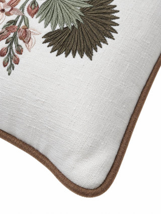 Close-up of the Palm cushion cover corner showing stitched olive and sage palm leaves, rose buds and brown piping on ivory fabric