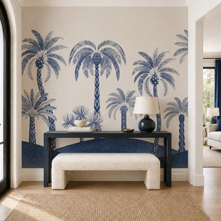 The Palmyra Breeze wallpaper mural in Cyanotype on an entryway wall, showing navy-and-white patterned-trunk palms behind a console table. view-foyer