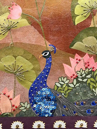 Close up of peacock motif featuring blue sequins for feathers and gold thread outlining on fabric.