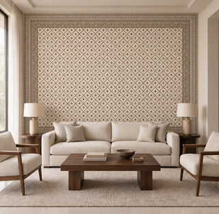 The Pera Vintage Ottoman beige wallpaper covering a living room feature wall in a fine diamond trellis pattern, framed by a decorative border, behind a cream sofa and wood armchairs.