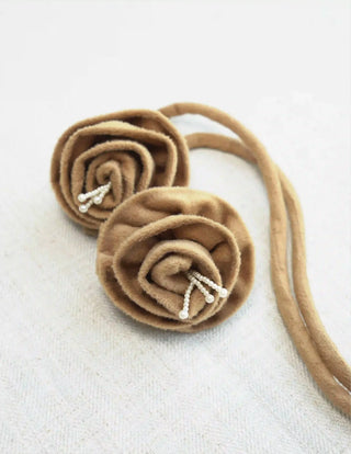 A high-resolution close-up of the sculpted camel flannel rose tassels accented with cascading strings of white pearls.