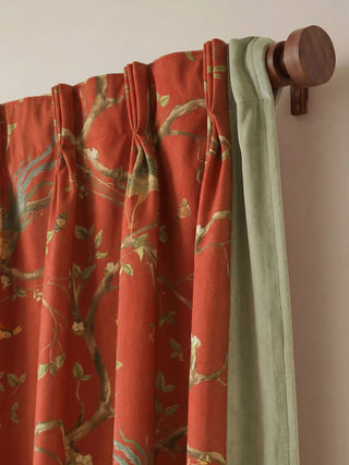 Close-up of the structured pinch-pleat tailoring and sage velvet header mounted on a wooden curtain rod.