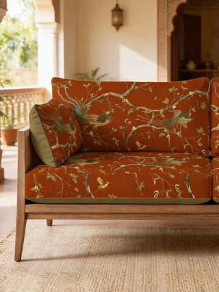 A luxury wooden-framed sofa upholstered in Phoenix Chinoiserie Rust fabric featuring hand-painted birds and botanical vines.