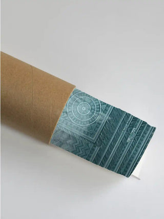 Pichwai cow mural wall art print in teal mist rolled in a kraft shipping tube, showing the carved medallion and chevron archway detail.