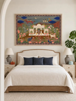 Pichwai Palace embroidered wall art in a pale wood frame above an upholstered bed with cream bedding and inlaid bedside tables in a bedroom
