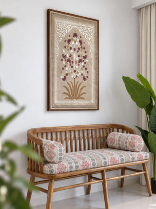 The Pietra wall art in a dark wood frame above a slatted wooden bench with a printed seat cushion and bolsters, beside a leafy plant.