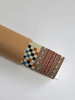 The Poetry wall art print partly unrolled from its shipping tube, showing a checkerboard grid beside a border of floral rosettes on rust red.