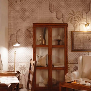 Alhambra's Whisper wallpaper with lattice arches and palm trees, behind a glass cabinet, armchair and tea table in a sitting room