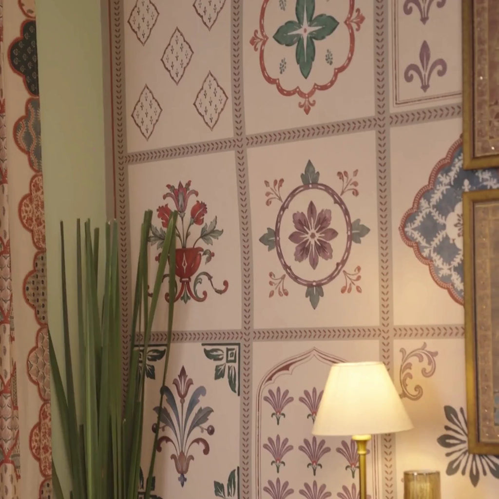 Chitrangan wallpaper in a tiled grid of floral rosettes and niches, behind brass lamps, framed art and a festive dining table