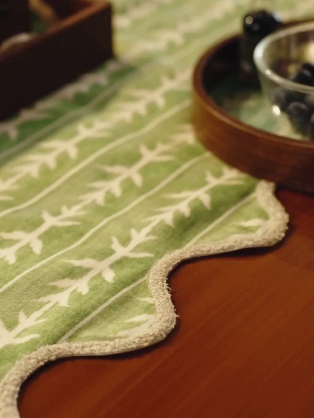 Garden Gala table runner in sage green with cream leaf sprigs and scalloped edges, running down a dining table set for tea