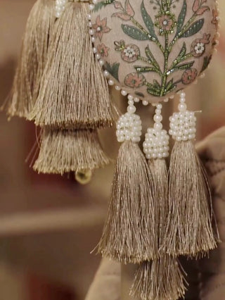 Gulbano curtain tieback with two padded teardrop pods embroidered in green leaves, pearl bead strands and tassels on a curtain