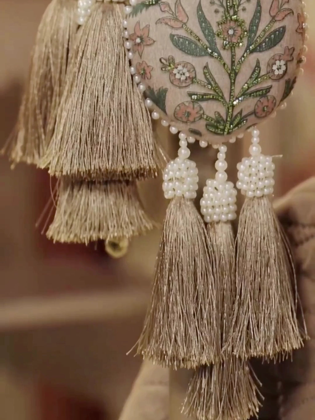 Gulbano curtain tieback with two padded teardrop pods embroidered in green leaves, pearl bead strands and tassels on a curtain