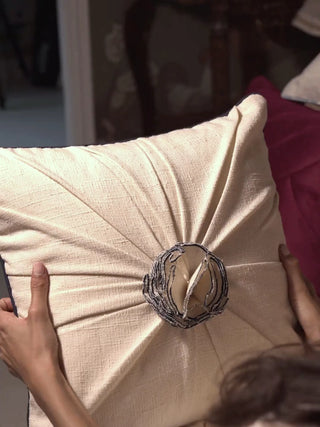 Close-up video of the Ivory Gardenia pleated rosette cushion cover, showing the radiating ivory pleats and the grey corded rosette at the centre