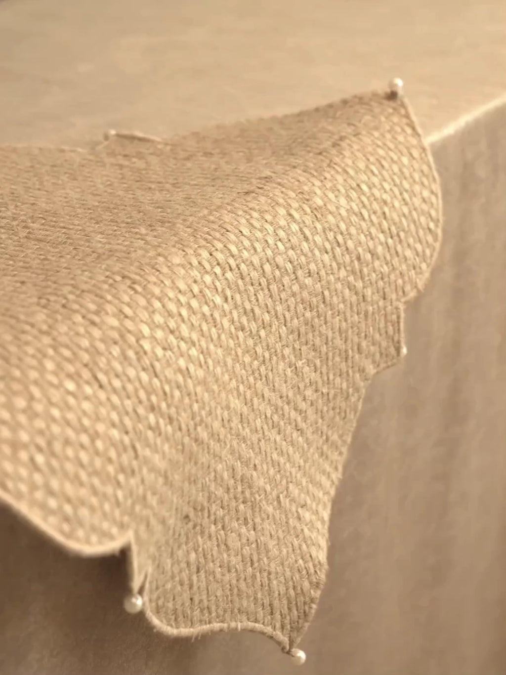 Kasbah Pearl jute table runner with scalloped Moroccan medallions and pearl-tipped points, laid on a table with a plate and flowers