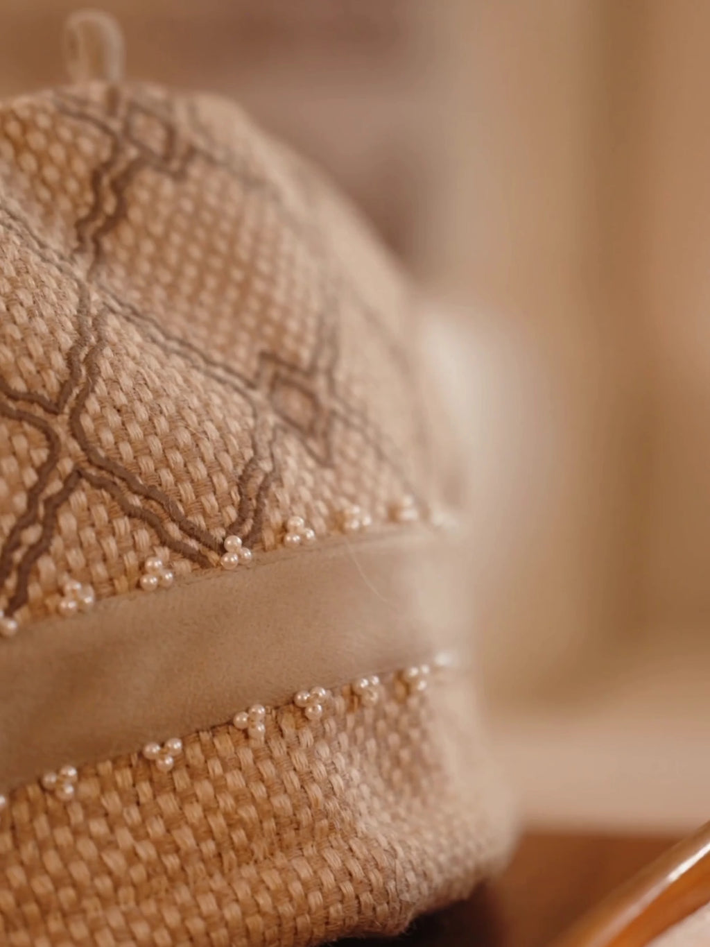 Oat Pearl tea cosy with basket-weave jute, grey lattice embroidery and pearl beads, placed over a teapot on a wooden tea tray