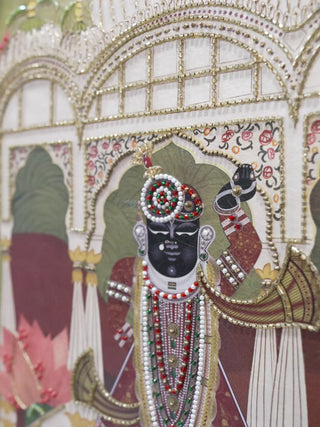 Pichwai Palace embroidered wall art: Shrinathji in a white pavilion, a beaded peacock, a figure in a chariot and the framed piece on a wall