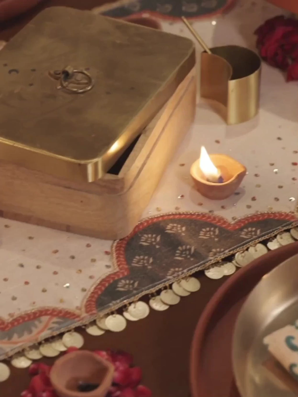 Riwaayat table runner with scalloped arch panels and coin edging, under brass thalis, diyas, candles and rose petals on a festive table