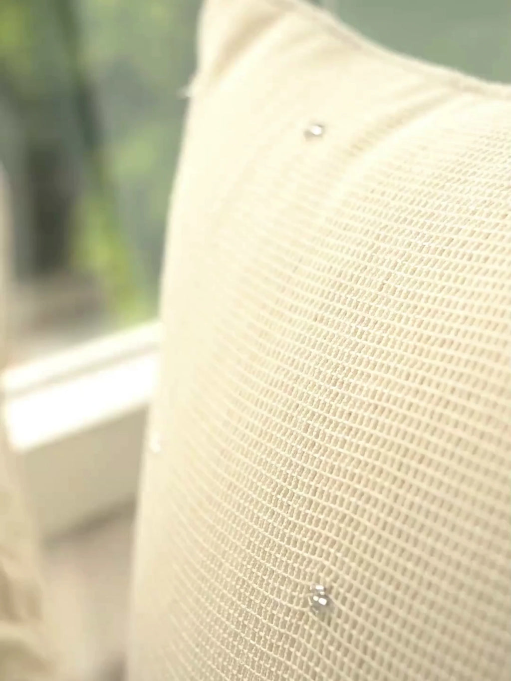 Stardust cushion cover in ivory open-weave linen with scattered tiny beads, up close and on a window seat beside white flowers