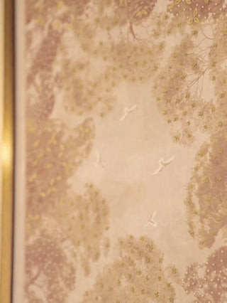 Close view of The Forest Nest wall art in gold and burgundy, then the framed print above a cream sofa between brass wall sconces
