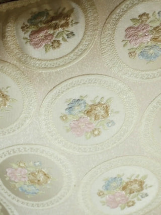 Close-up video of the Vintage Medallion Floral cushion cover, moving over cream jacquard roundels of pastel embroidered roses and the tasselled edge