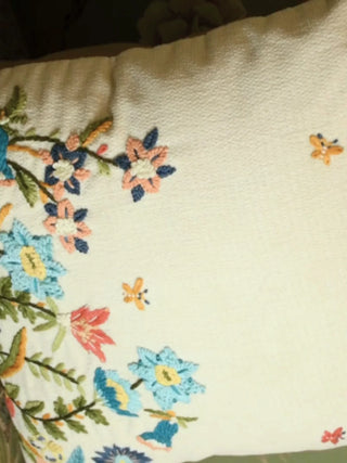 Close-up video of the Whispers of Spring cushion cover, moving over embroidered wildflowers, blue blooms and tiny butterflies on ivory textured linen