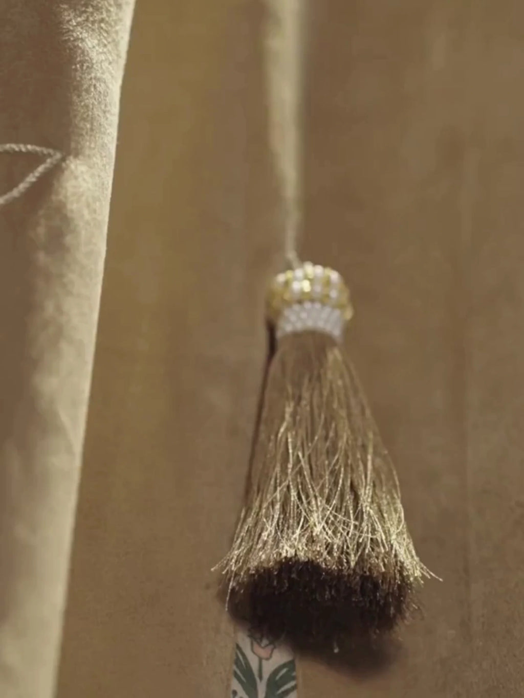 Zarqash readymade curtain in gold-beige with a hanging silk tassel and a floral embroidered border, shown up close in a warm room
